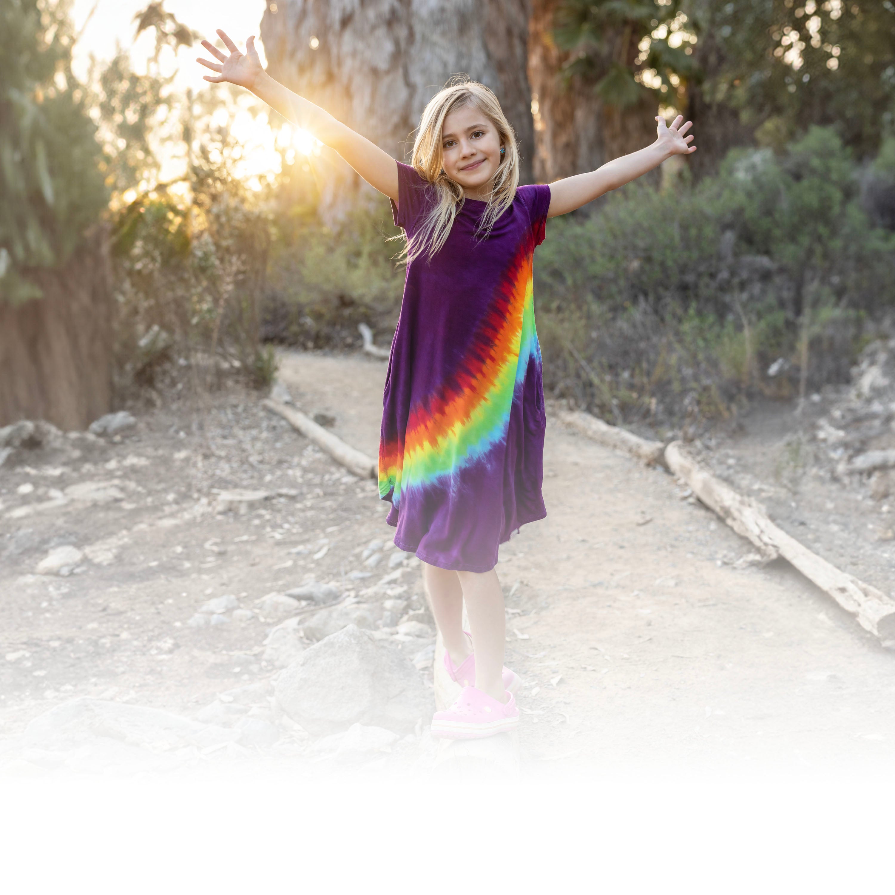 Girl in rainbow sensory dress with arms up