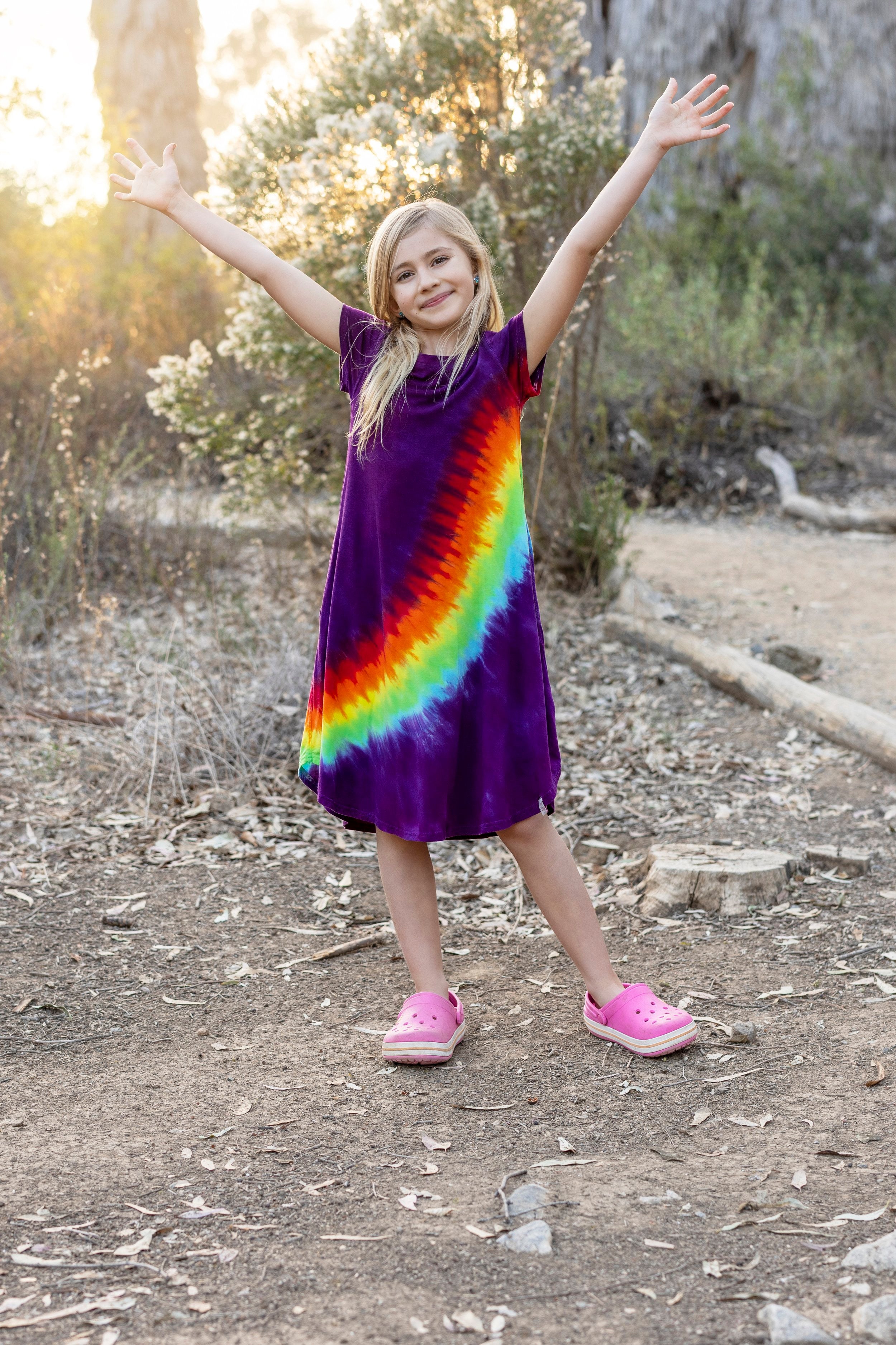 girl in soft rainbow dress with arms up