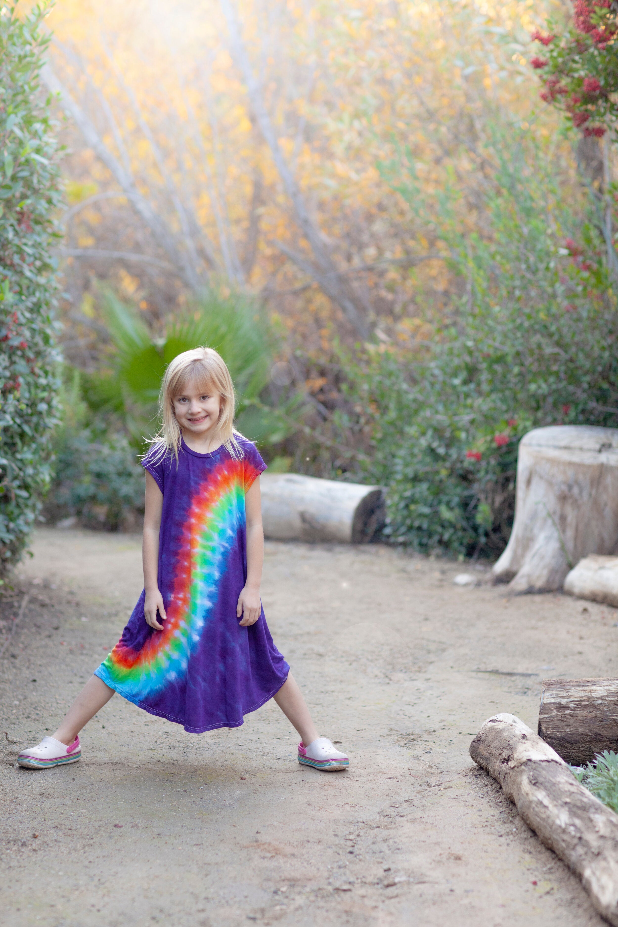 girls in rainbow sensory friendly dress standing on a path with bushes behind