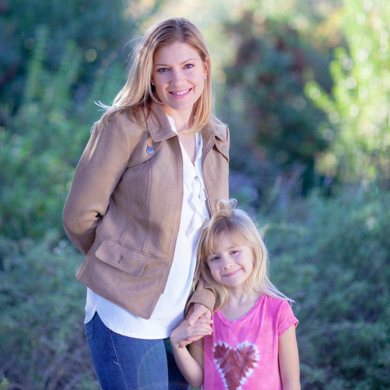 woman in tan jacket and girl in pink dress